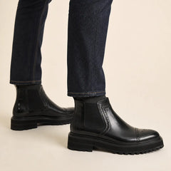 Black brogued Chelsea boot with lug sole on foot