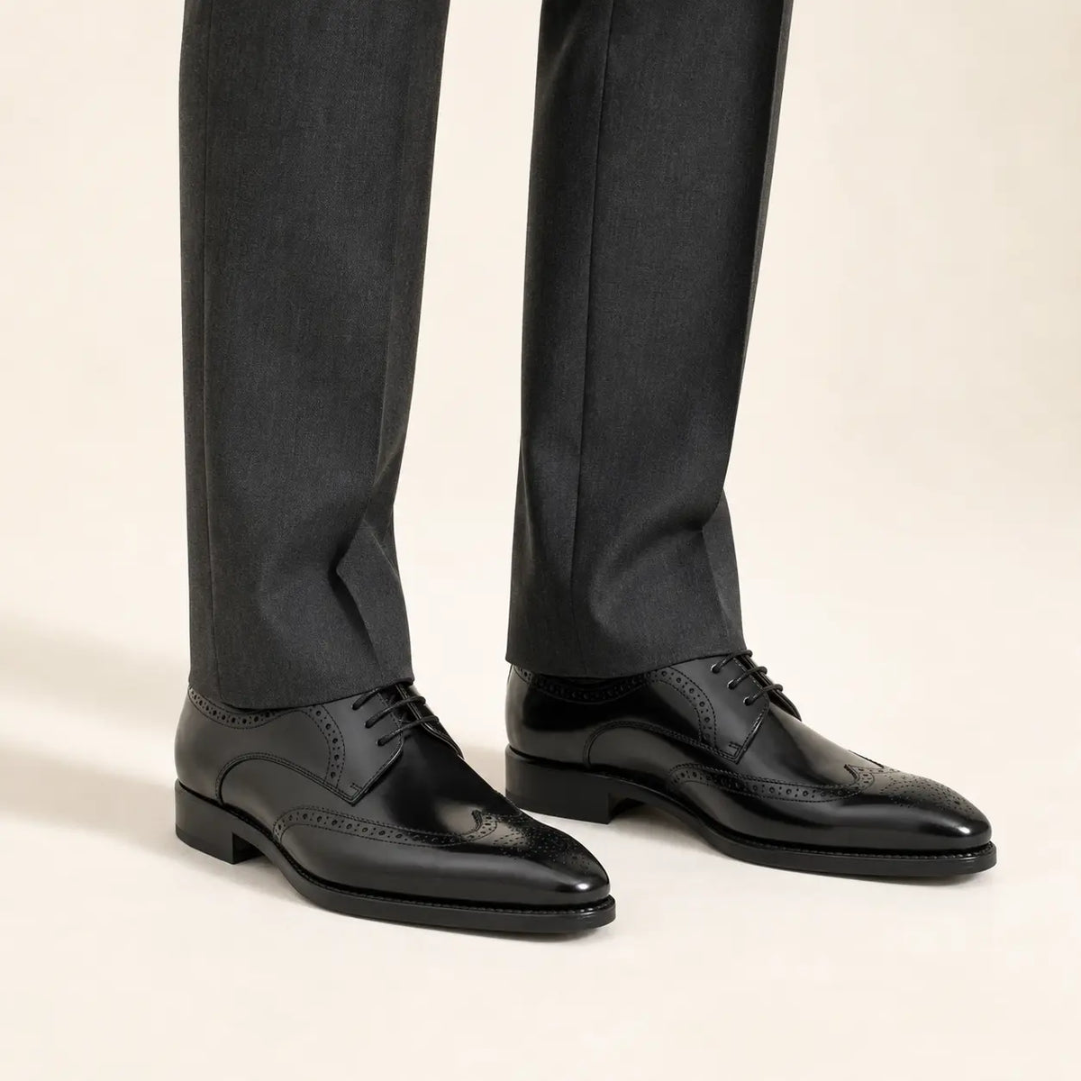 Black Burnished Wingtip Derby on foot, warm off-white studio