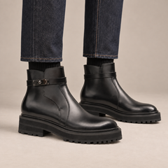 Black lug sole ankle boots with harness strap on foot