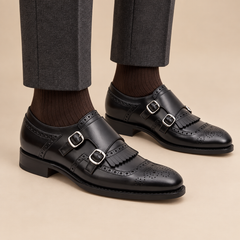 Black cap-toe double monk strap shoes with fringed vamp on model