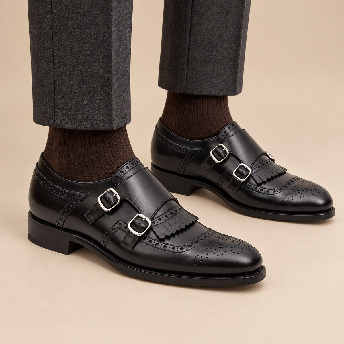 Black cap-toe double monk strap shoes with fringed vamp on model