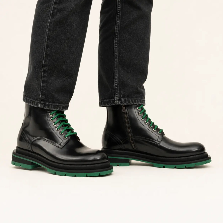 Black lace-up boots with green sole on-foot studio photo