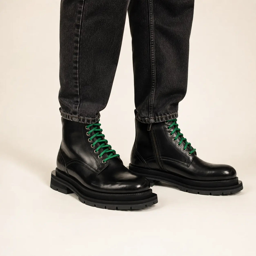 Black leather boots with green laces on-foot studio photo