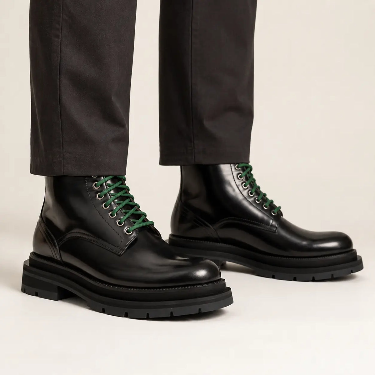 Black leather boots with green laces on-foot studio photo