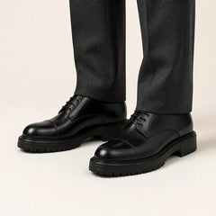 Black Lug Sole Derby on foot, warm off-white studio