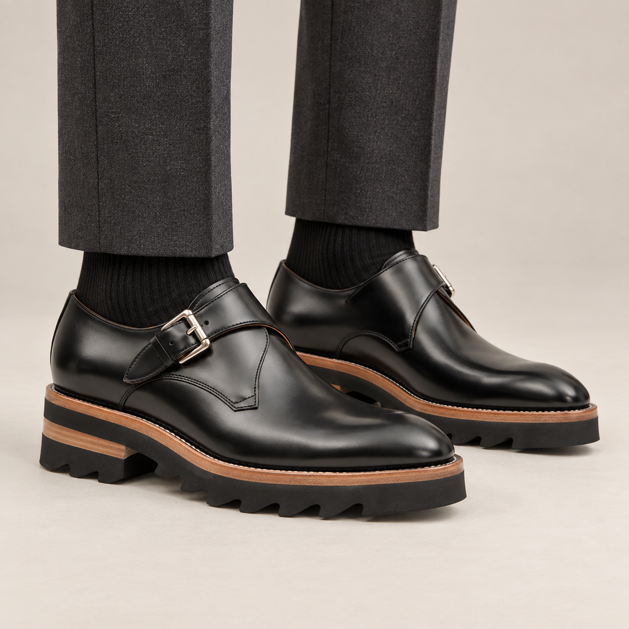Black plain-toe single monk strap shoes with brown-band lug sole — premium on-foot studio view