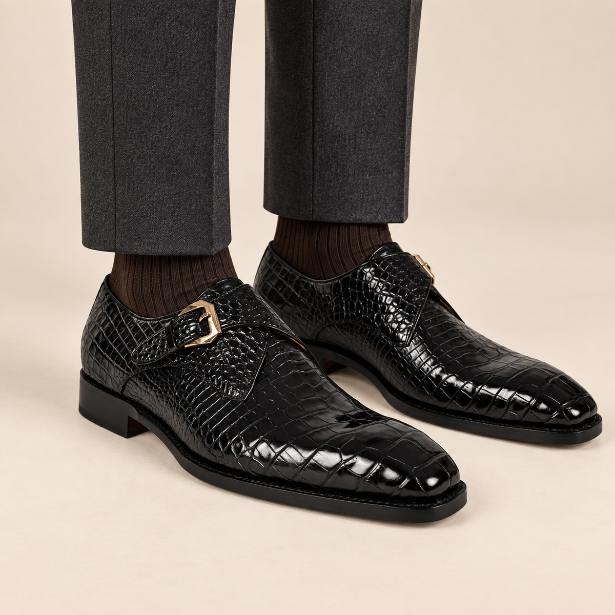 Black square-toe single monk shoes with glossy crocodile scale texture on feet
