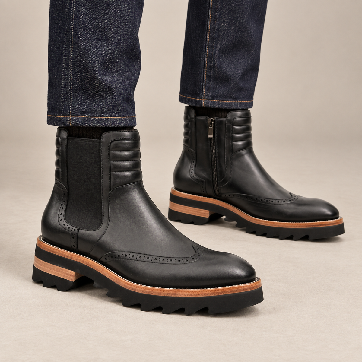 Black lug sole wingtip Chelsea ankle boots — on-foot studio view