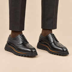 Black wingtip Derby shoes with brown-edge lug sole on model