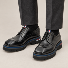 Black Wingtip Derby Shoes with Metal Eyelets — on-foot studio view