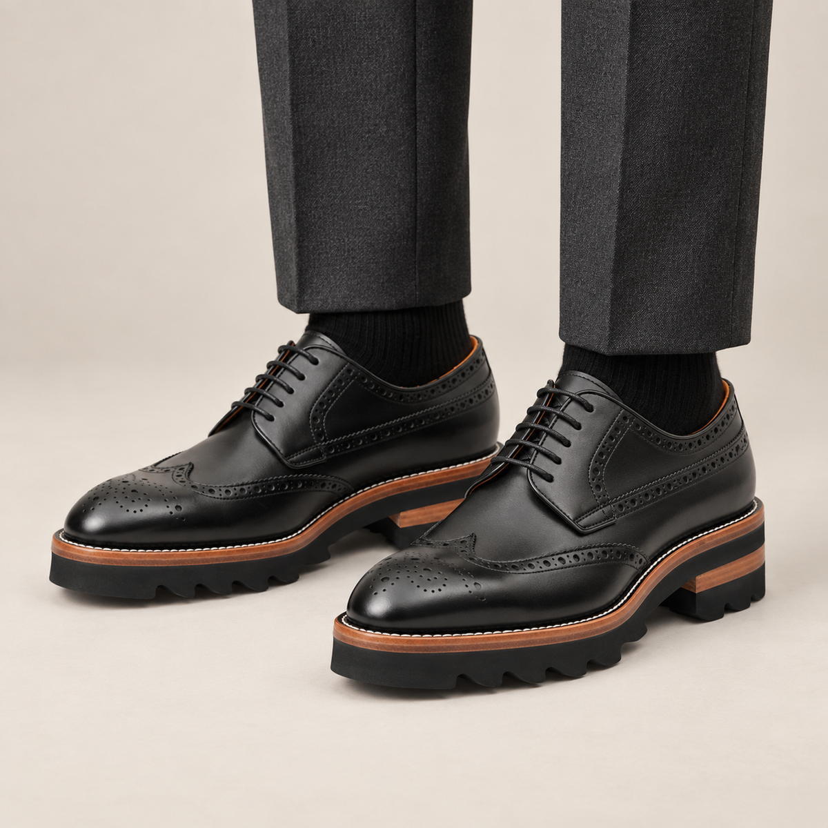 Black wingtip Derby shoes with brown-band lug sole — premium on-foot studio view