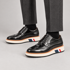 Black glossy wingtip Derby shoes with contrast platform sole — premium on-foot studio view