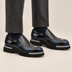 DIVINCH blue-shaded black glossy wingtip slip-on shoes worn with tailored charcoal trousers