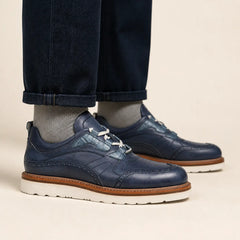 Blue brogue casual shoes with white sole on foot