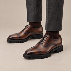 Brown cap-toe Oxford shoes worn on foot, without shoe trees