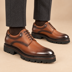 Brown plain-toe Derby shoes with lug sole on model