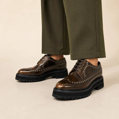 Brown polished chunky wingtip Derby worn with deep-olive wide-leg trousers