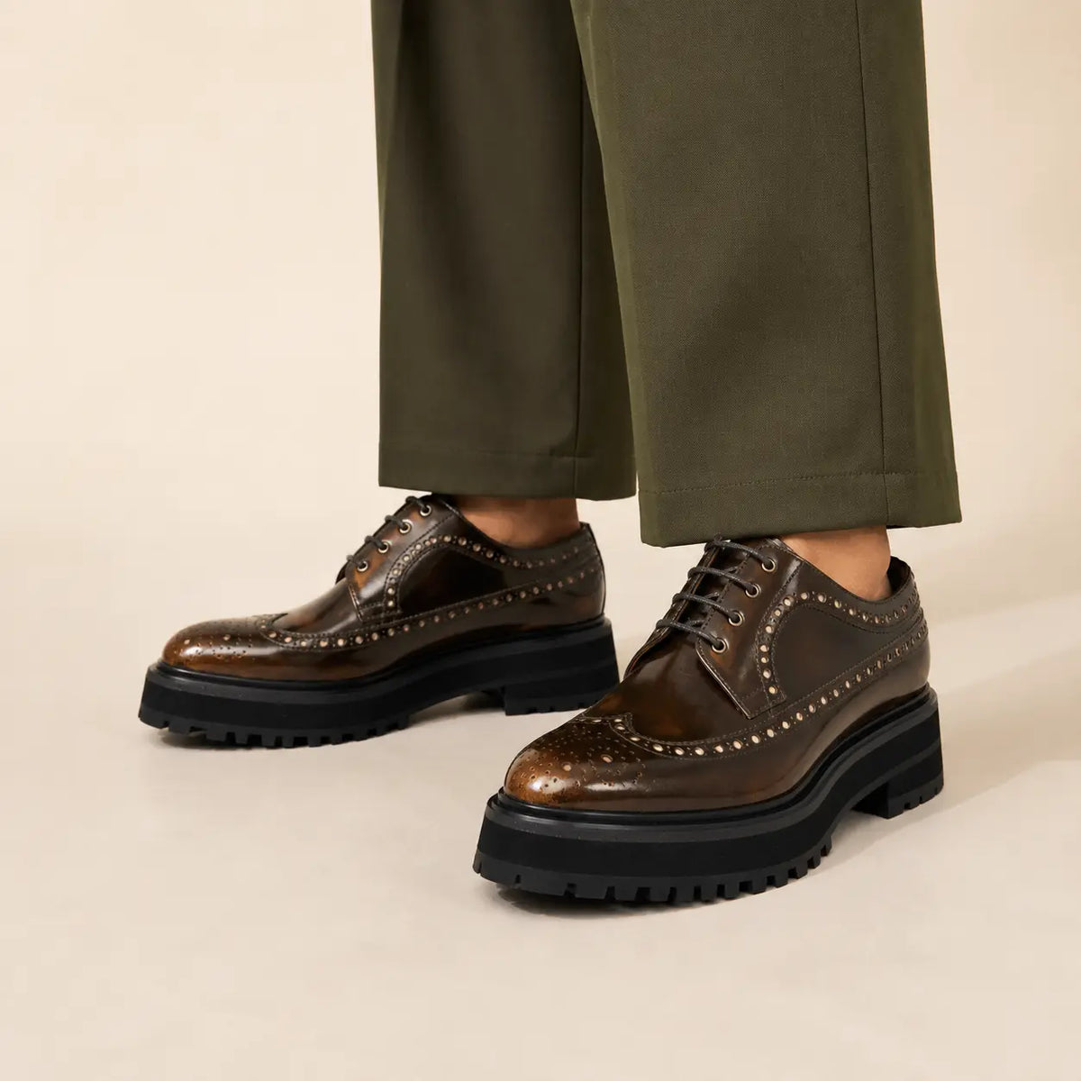 Brown polished chunky wingtip Derby worn with deep-olive wide-leg trousers