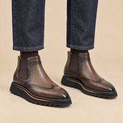 Brown wingtip Chelsea boots with brown-edge lug sole on model