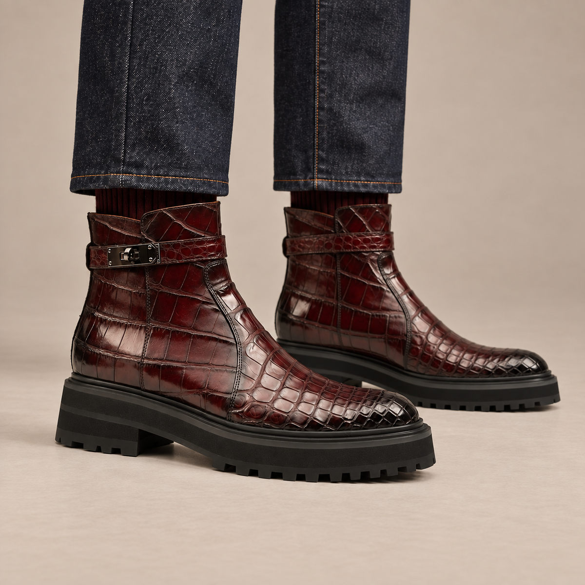 Burgundy crocodile-textured lug sole ankle boots with harness strap on foot