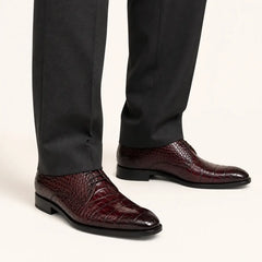 Burgundy crocodile Derby shoes worn with charcoal tailored trousers in a warm studio.
