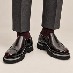DIVINCH burgundy-shaded black glossy wingtip slip-on shoes worn with tailored charcoal trousers