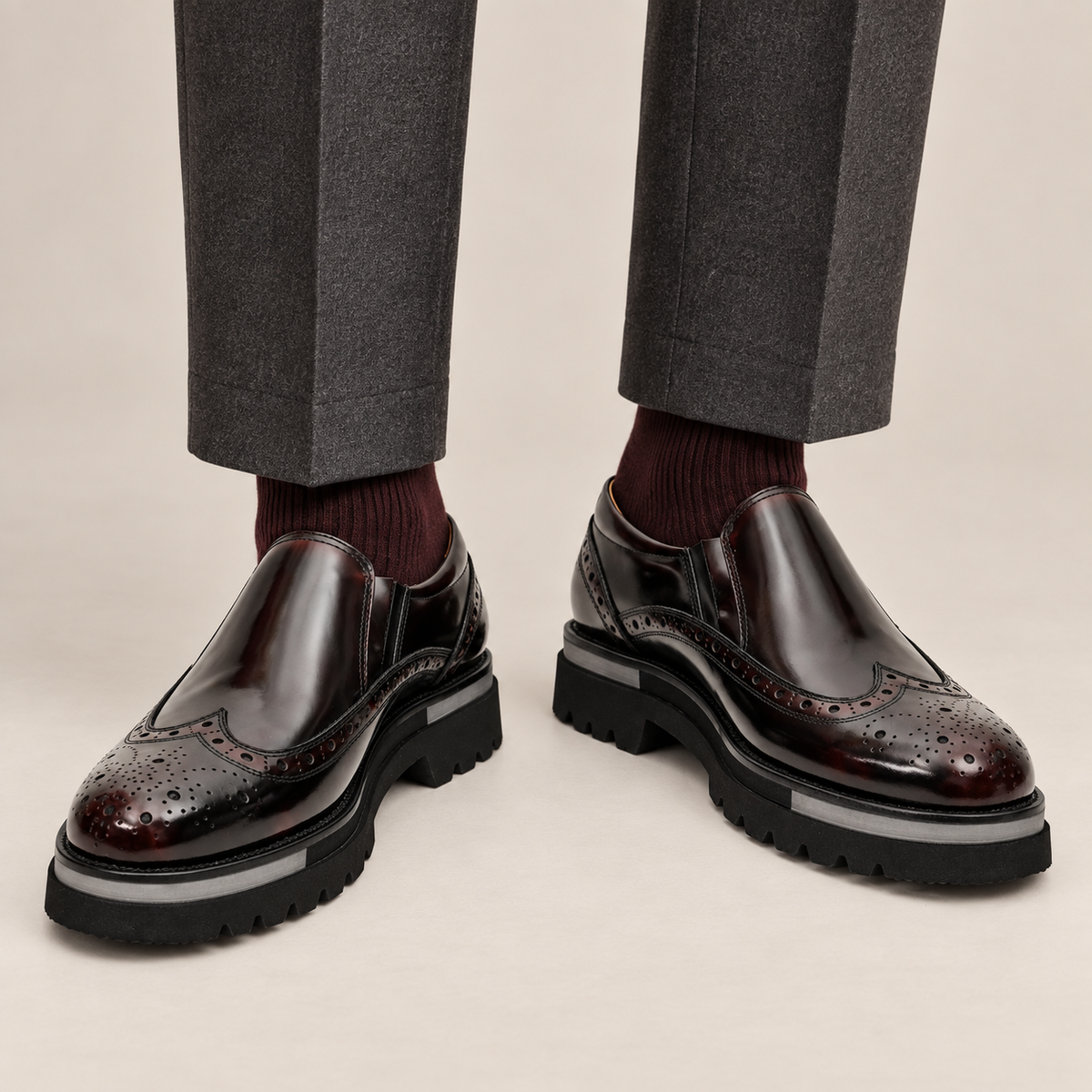 DIVINCH burgundy-shaded black glossy wingtip slip-on shoes worn with tailored charcoal trousers