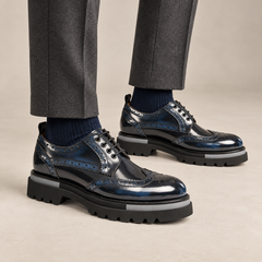 Dark blue-black wingtip Derby shoes with gray sole accents — on-foot studio view