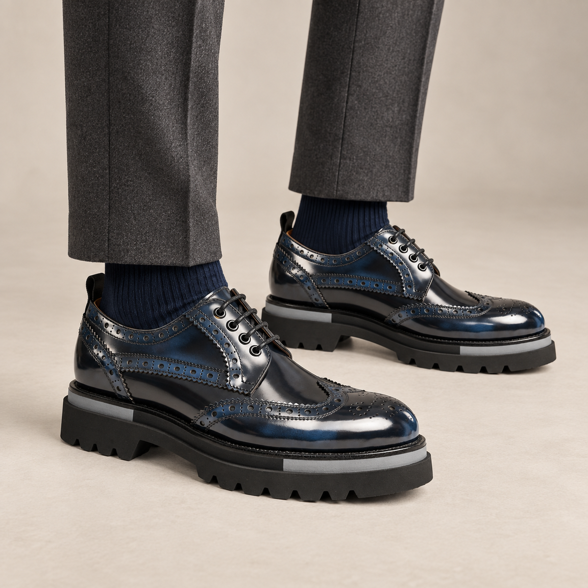Dark blue-black wingtip Derby shoes with gray sole accents — on-foot studio view