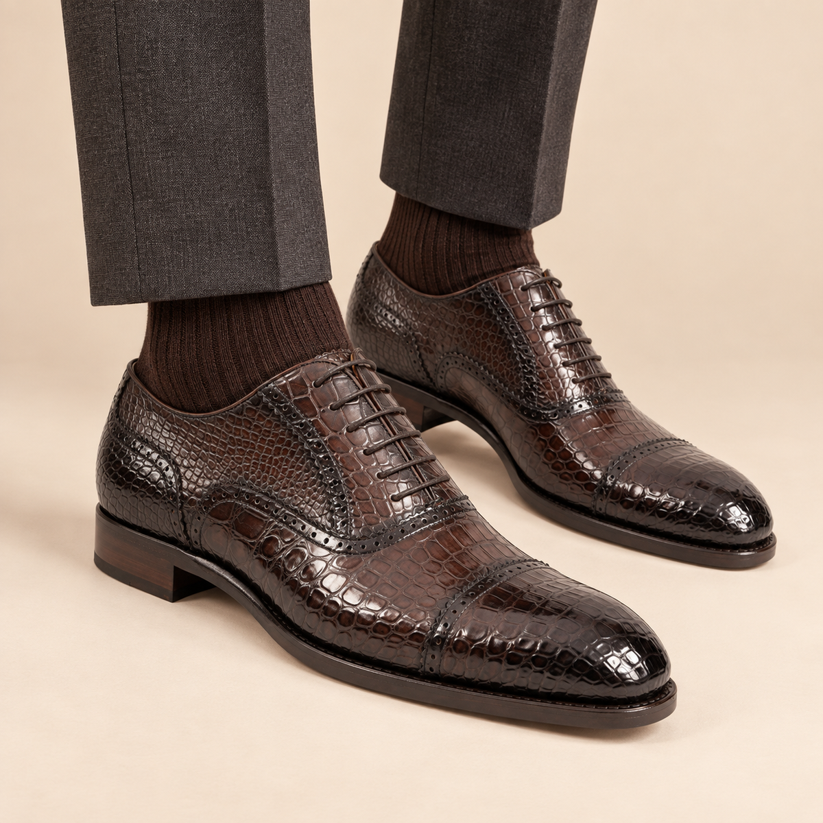 Dark brown crocodile-embossed cap-toe Oxford shoes with perforated detail on model