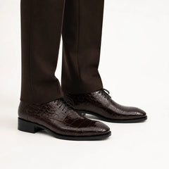 Dark brown crocodile-textured Derby shoes on foot