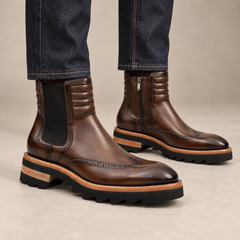 Dark brown lug sole wingtip Chelsea ankle boots — on-foot studio view