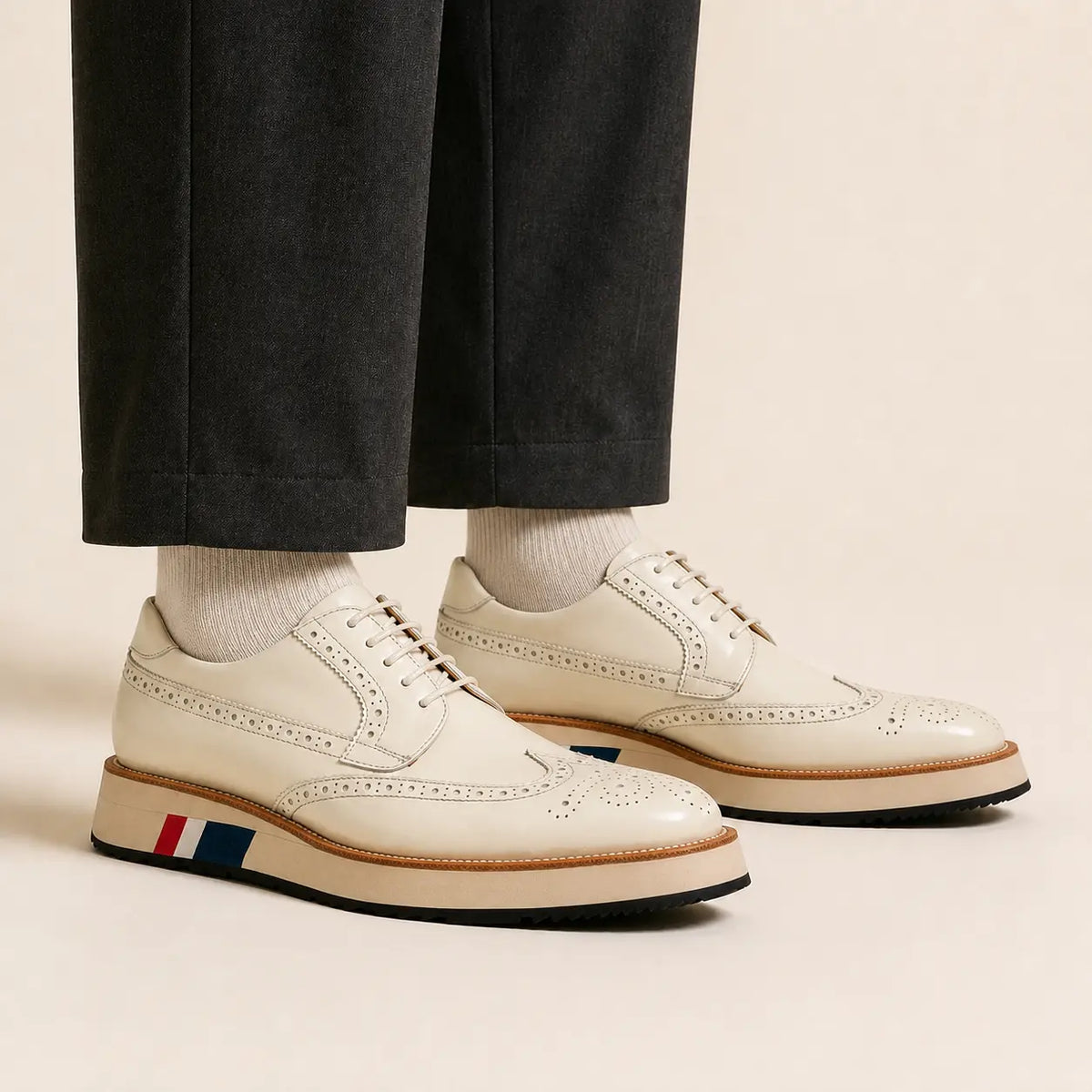 Low-cut ivory brogue Derby shoes worn with charcoal wide-leg trousers and ivory socks