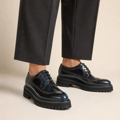 Midnight-blue chunky wingtip Derby worn with deep-charcoal wide-leg trousers