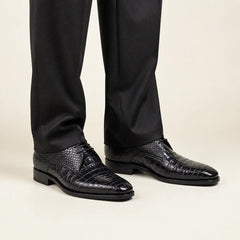 Midnight crocodile Derby shoes worn with charcoal tailored trousers in a warm studio.