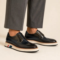 Dark navy and brown brogue Derby with contrast sole worn with warm-gray wide-leg trousers