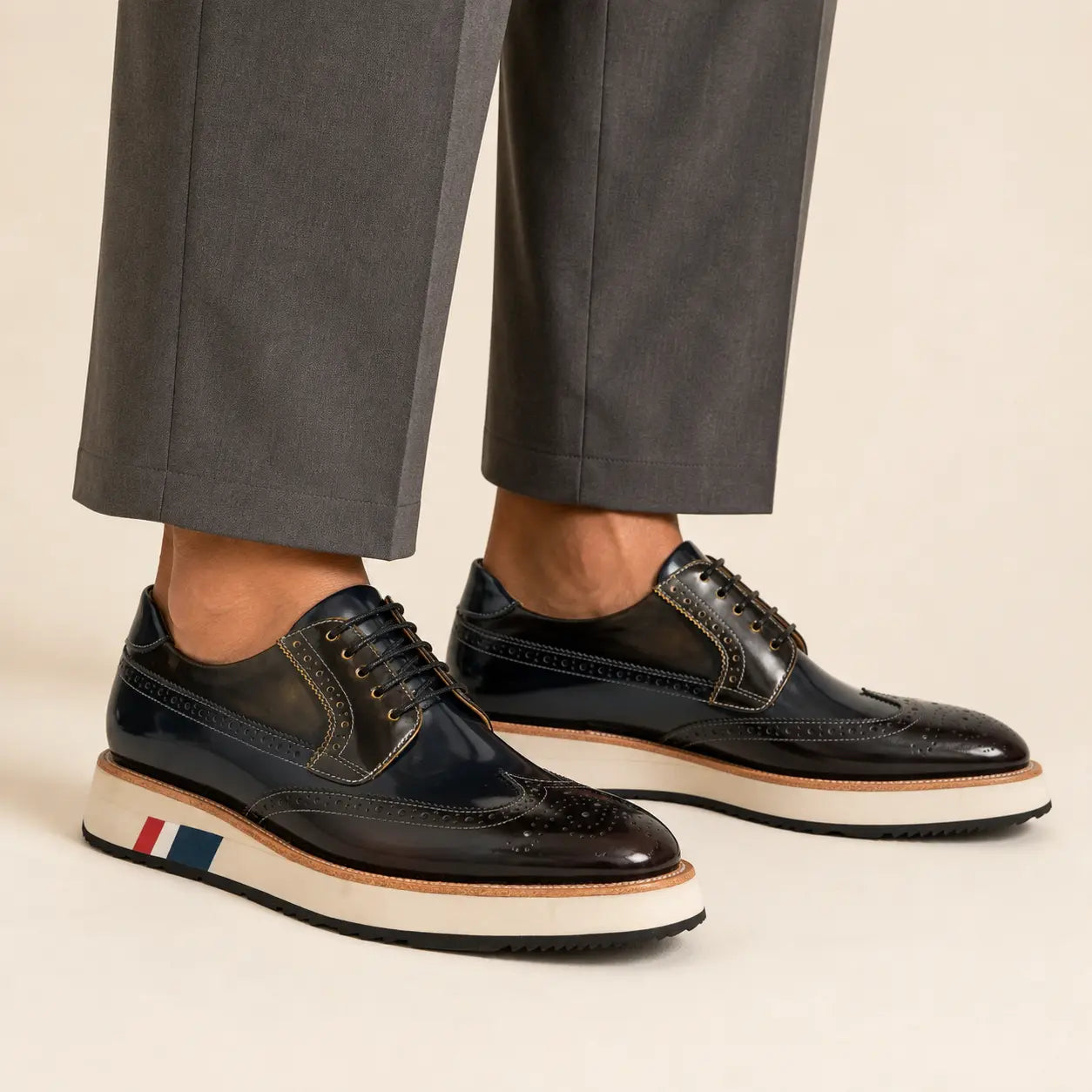 Dark navy and brown brogue Derby with contrast sole worn with warm-gray wide-leg trousers