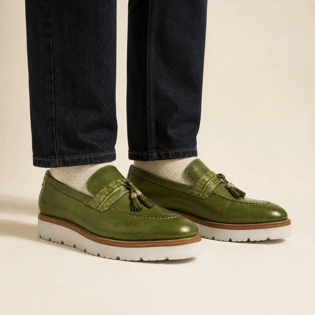 Olive green crocodile-effect tassel loafer on foot