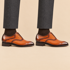 Orange-brown square-toe Oxford shoes with raised-texture panels worn with tailored trousers