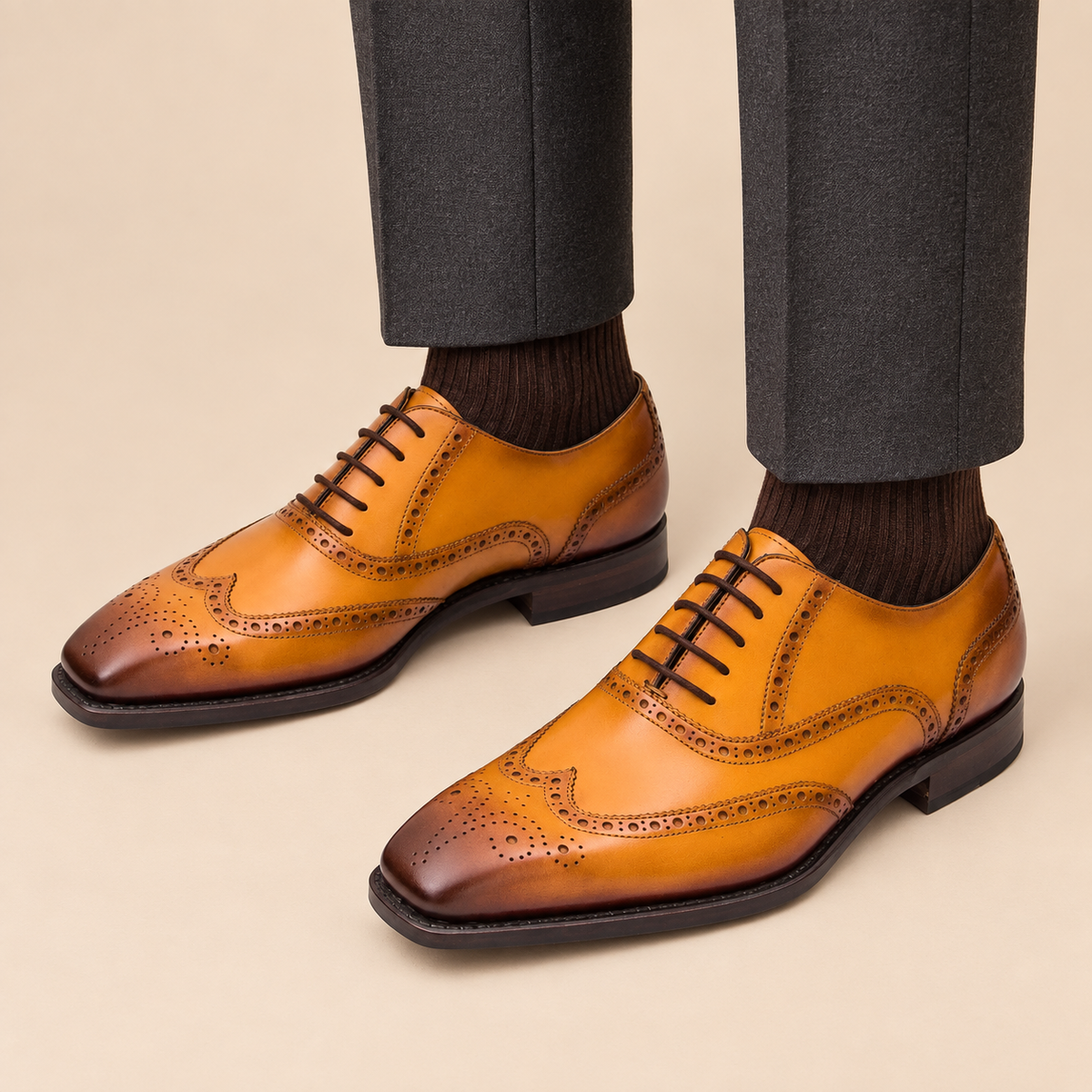 Golden tan square wingtip Oxford shoes with medallion on model