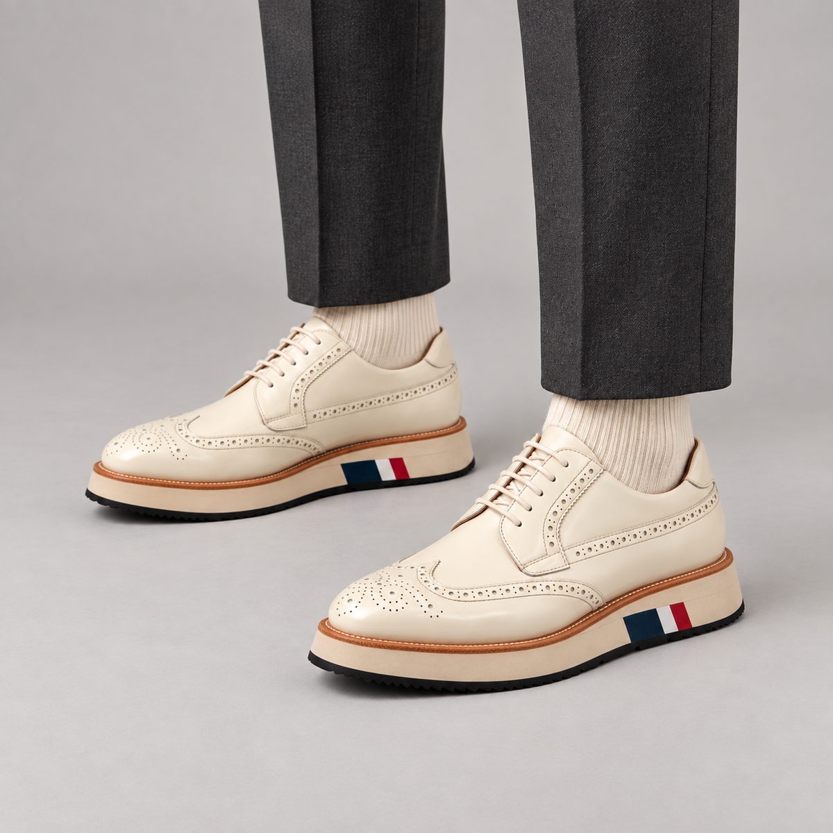 Ivory wingtip Derby shoes with contrast platform sole — premium on-foot studio view